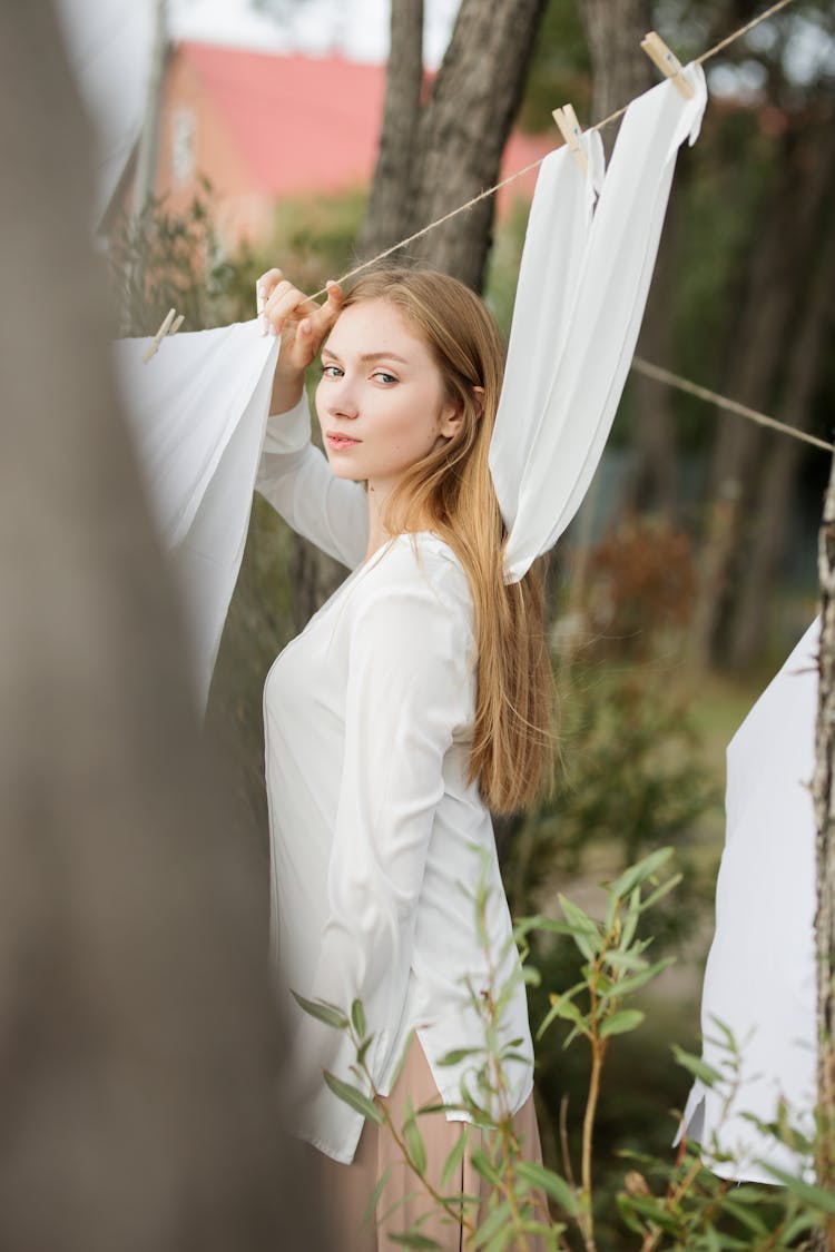 Woman In White Long Sleeve Shirt Holding A String With Hanging Clothes