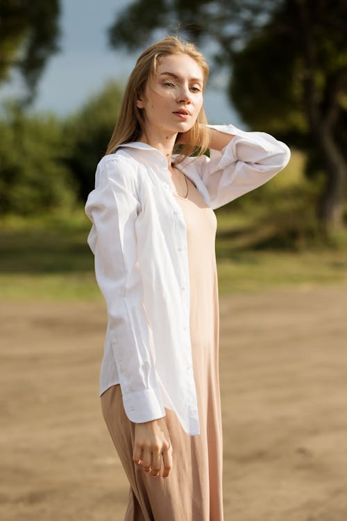 Woman in White Long Sleeve Shirt Standing on Brown Field