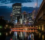 夜晚，河流倒映着现代建筑，照亮了大阪的城市景观