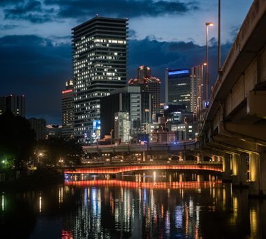 夜晚，河流倒映着现代建筑，照亮了大阪的城市景观