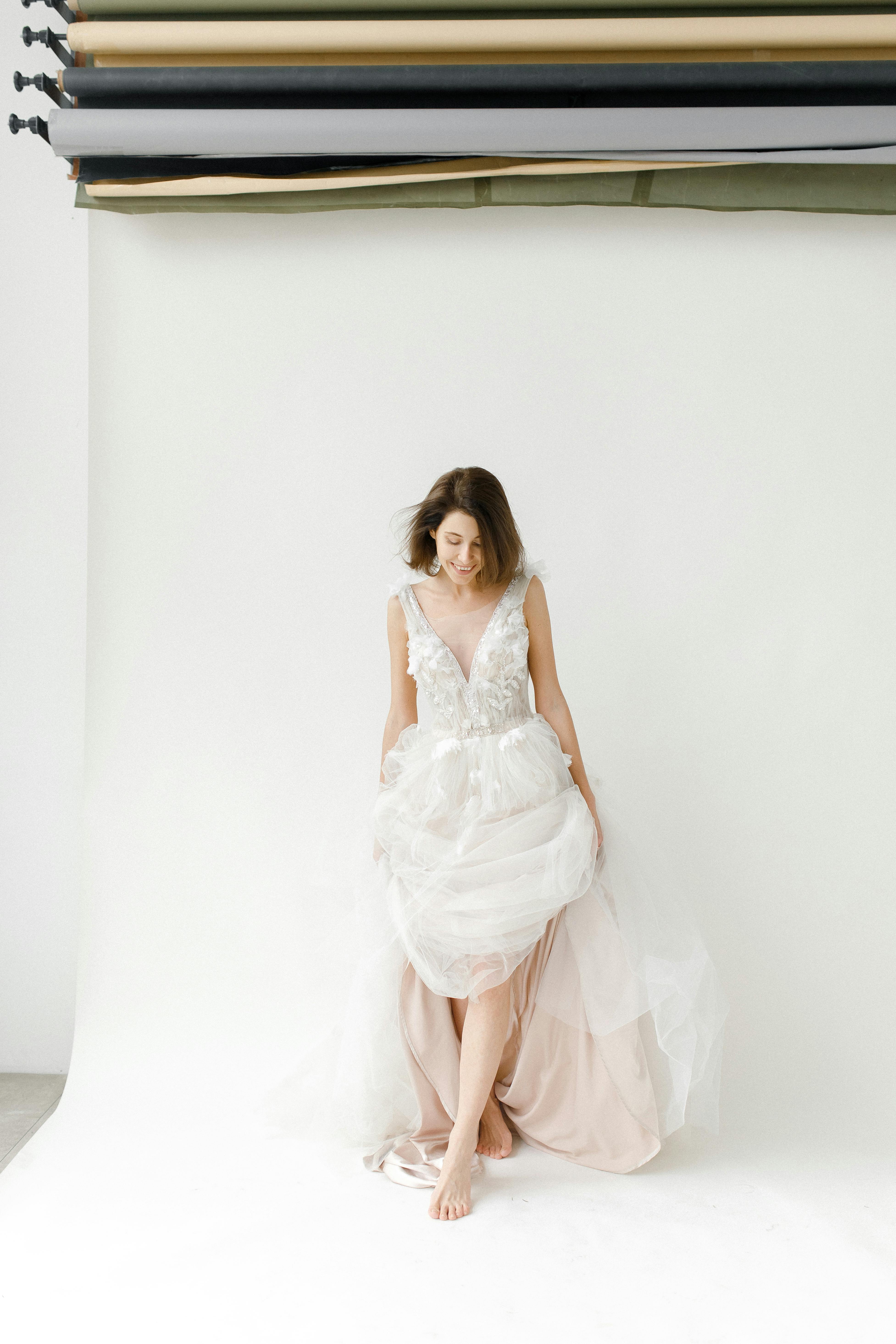 Beautiful studio portrait of a barefoot bride in an elegant white wedding gown, exuding timeless grace.