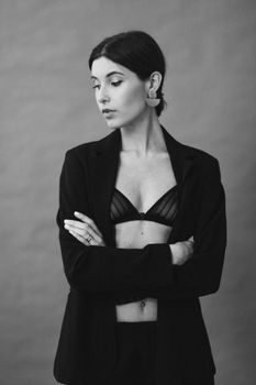 Black and white studio portrait of a stylish woman in a suit and bra.