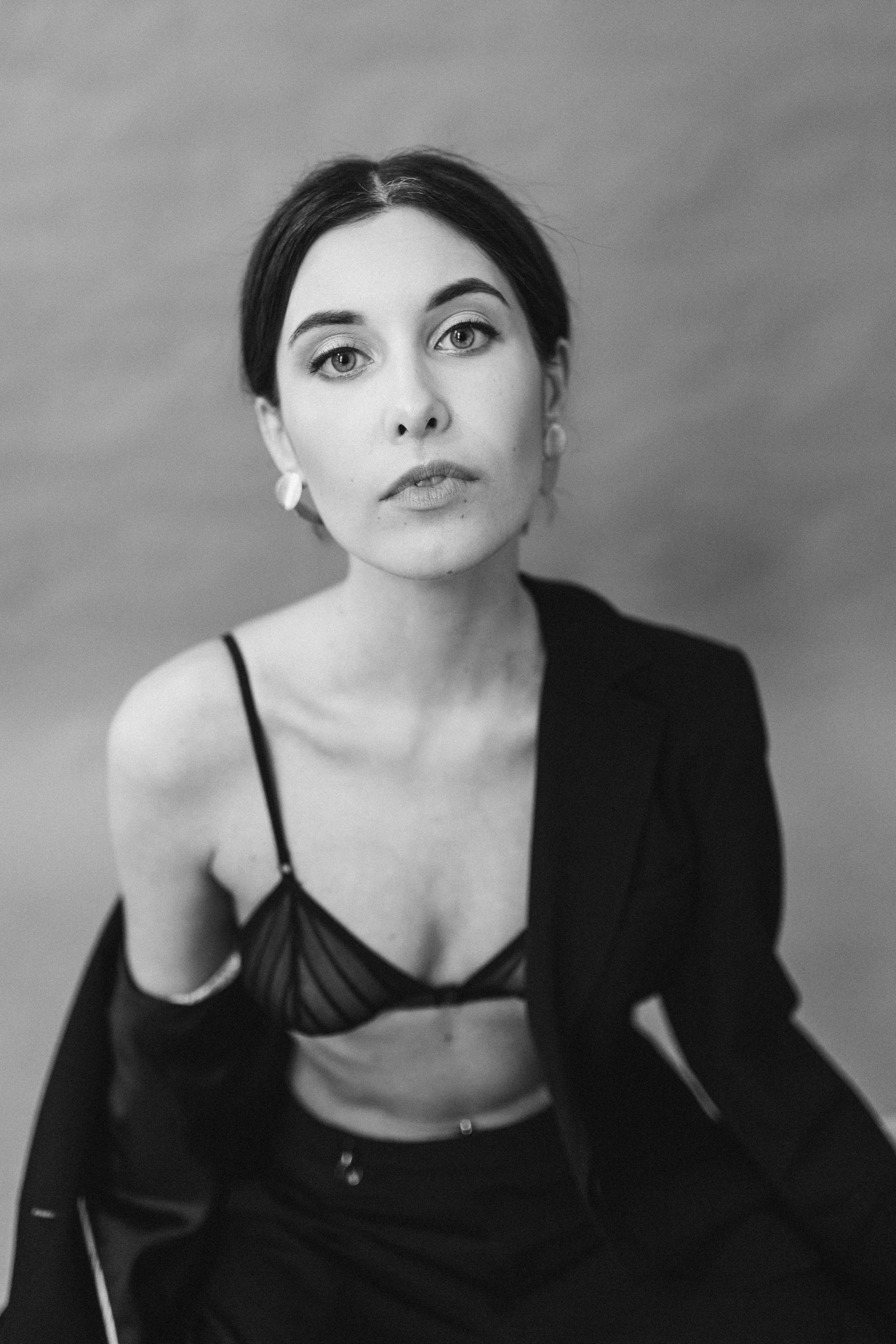 Elegantly posed woman in a monochrome studio shot, exuding confidence.