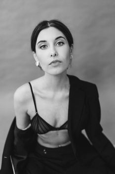 Elegantly posed woman in a monochrome studio shot, exuding confidence.