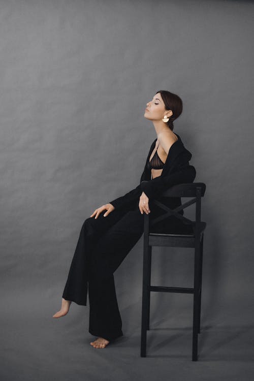 Woman in Black Dress Sitting on Black Chair