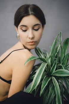 Portrait of a serene woman with a green plant, highlighting elegance and nature.