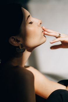 一个女人安详的侧脸轮廓，手放在唇边，沐浴在柔和的阴影中