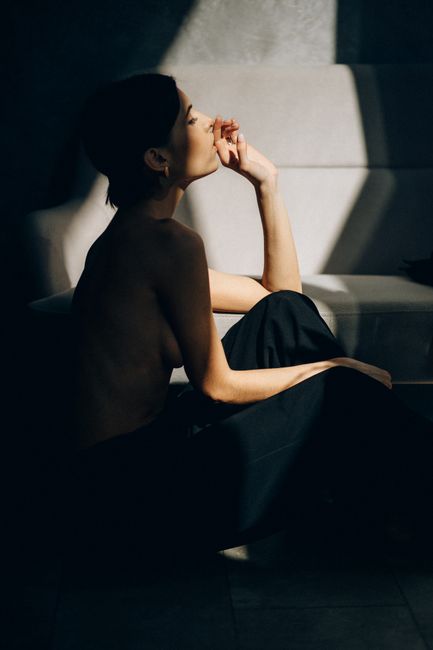 Elegant and moody portrait of a topless woman in dramatic lighting indoors.