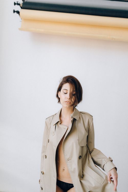 Fashion model posing in a trench coat against a studio backdrop