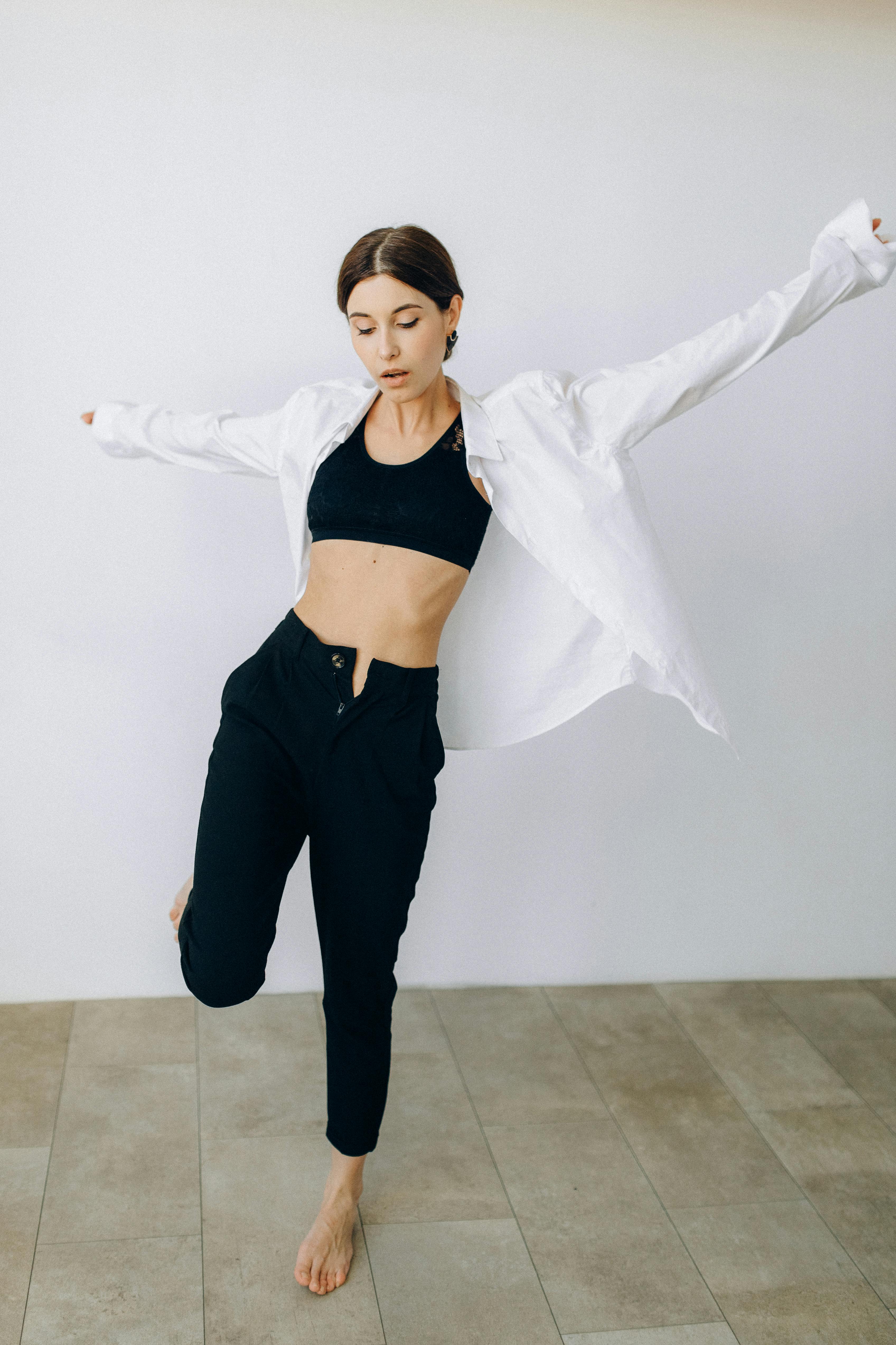 a woman in white long sleeves standing barefooted while raising her hands