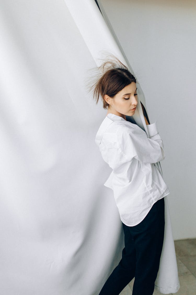 Woman In White Long Sleeves Holding A Curtain