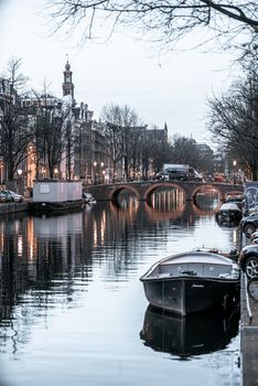 黄昏时分，阿姆斯特丹标志性的运河风景如画，船只倒映着城市灯光