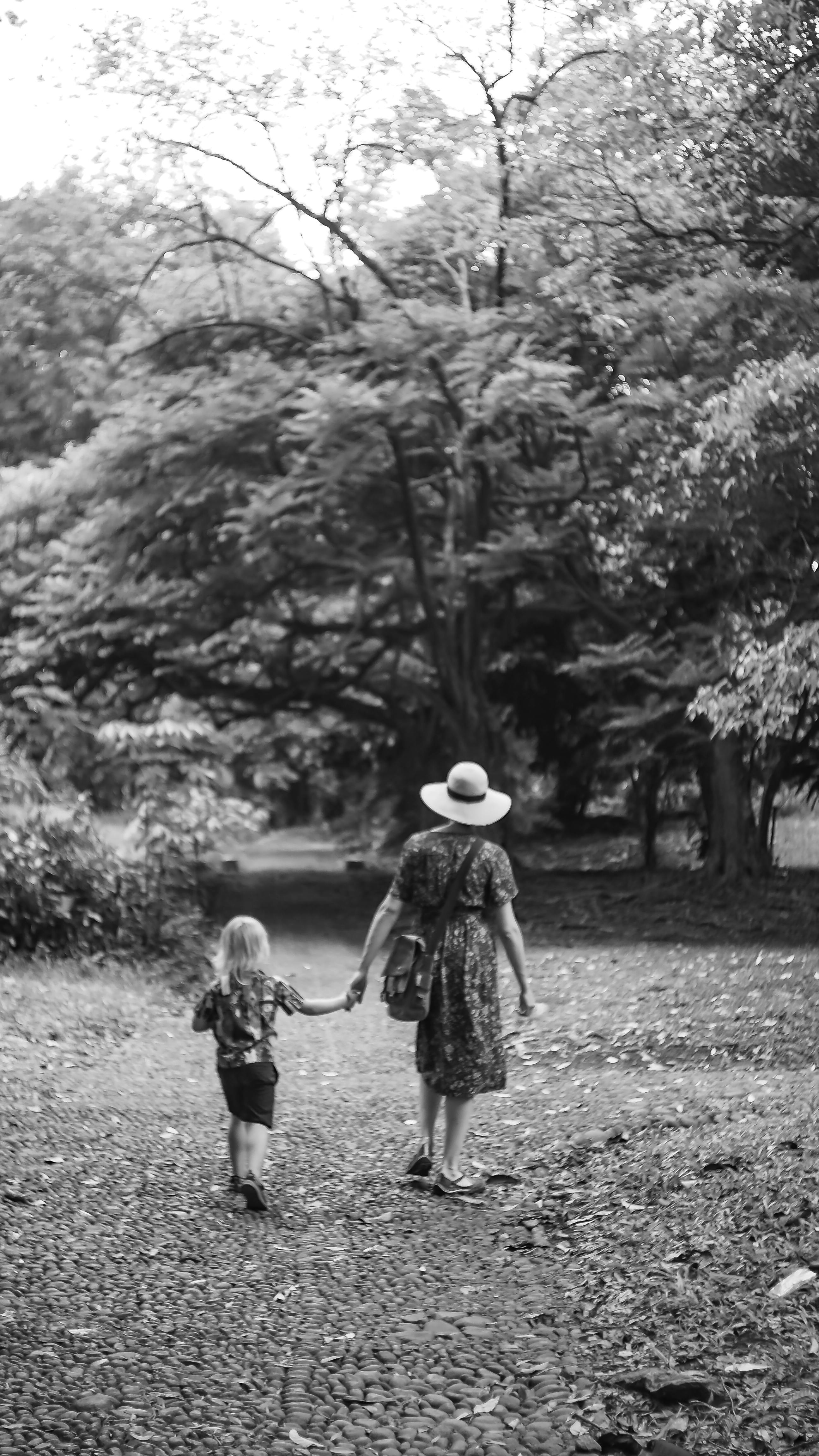 grayscale photo of a woman and a child walking in the park