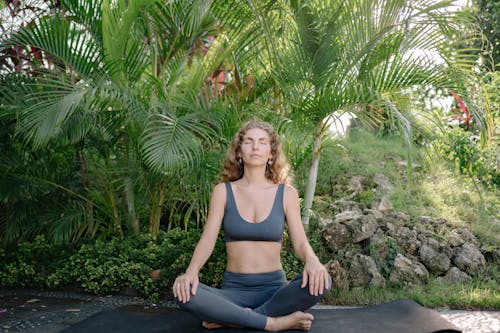Free Fit sportswoman meditating in lotus pose in park Stock Photo
