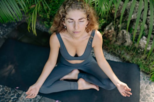 Woman practicing yoga meditation on mat, enjoying outdoor tranquility.