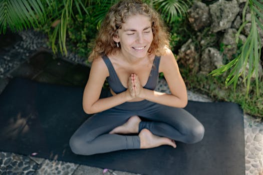 Woman practicing yoga outdoors with closed eyes and a serene smile.