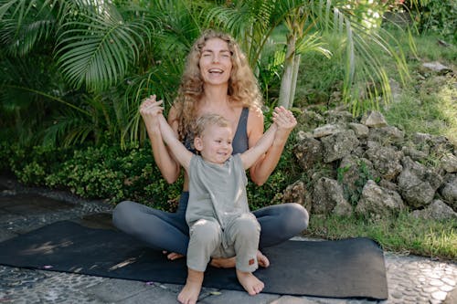 Woman Sitting on Yoga Mat with Boy on Her Lap