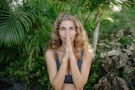 一位女子在绿树环绕、郁郁葱葱的热带环境中宁静地练习冥想