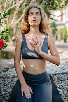 A woman in serene meditation and yoga practice outdoors, surrounded by nature.