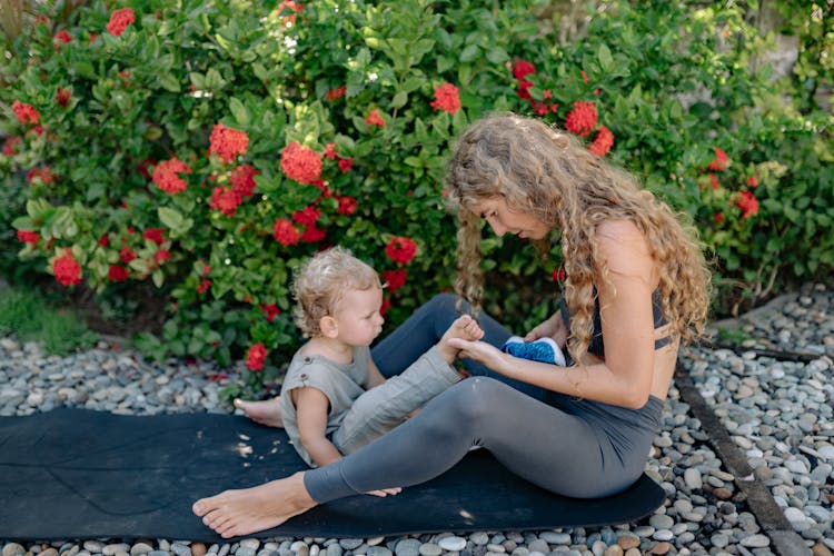 Mother And Son Resting On Yoga Mat In Garden