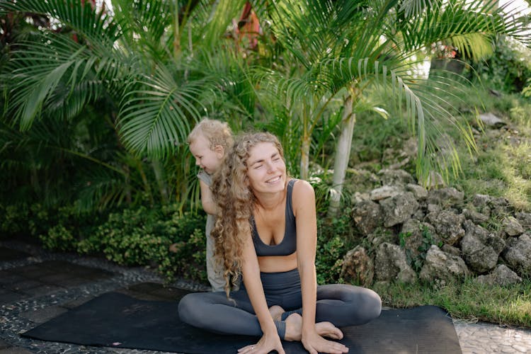 Cute Little Boy Behind Mothers Back On Yoga Mat