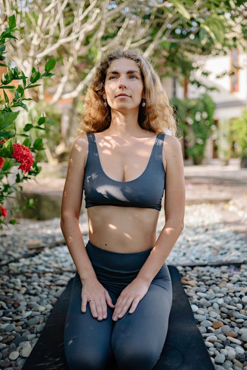 Content sportswoman sitting on yoga mat in garden