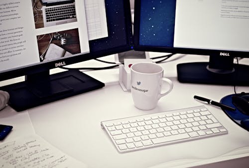 Free White Ceramic Mug Between Apple Magic Keyboard and Two Flat Screen Computer Monitors Stock Photo