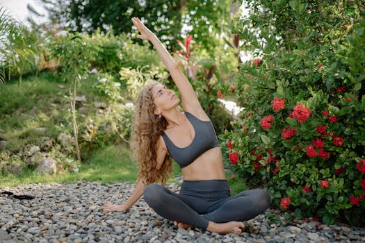 A woman practicing yoga outdoors in a serene garden with blooming red flowers, embodying peace and tranquility.