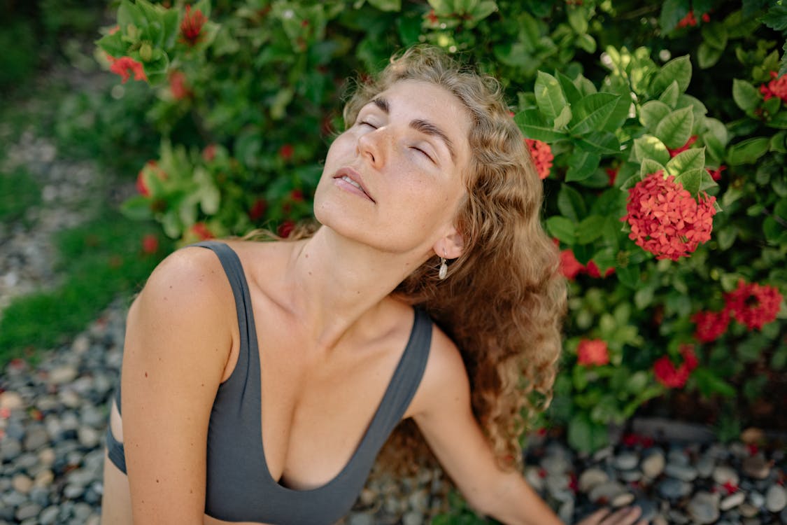 Free Woman in Gray Crop Top Near Red Flowers Stock Photo