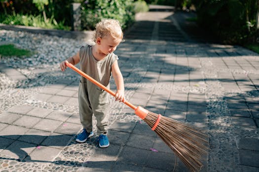 Charming Child Sweeping Concrete Pavement with Broomstick with the Quote "If you owe the bank $100 that's your problem. If you owe the bank $100 million, that's the bank's problem." written on it and have average color value #6A6E67