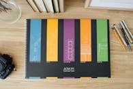 木桌上放着色彩缤纷的蓝图设计和建筑工作簿