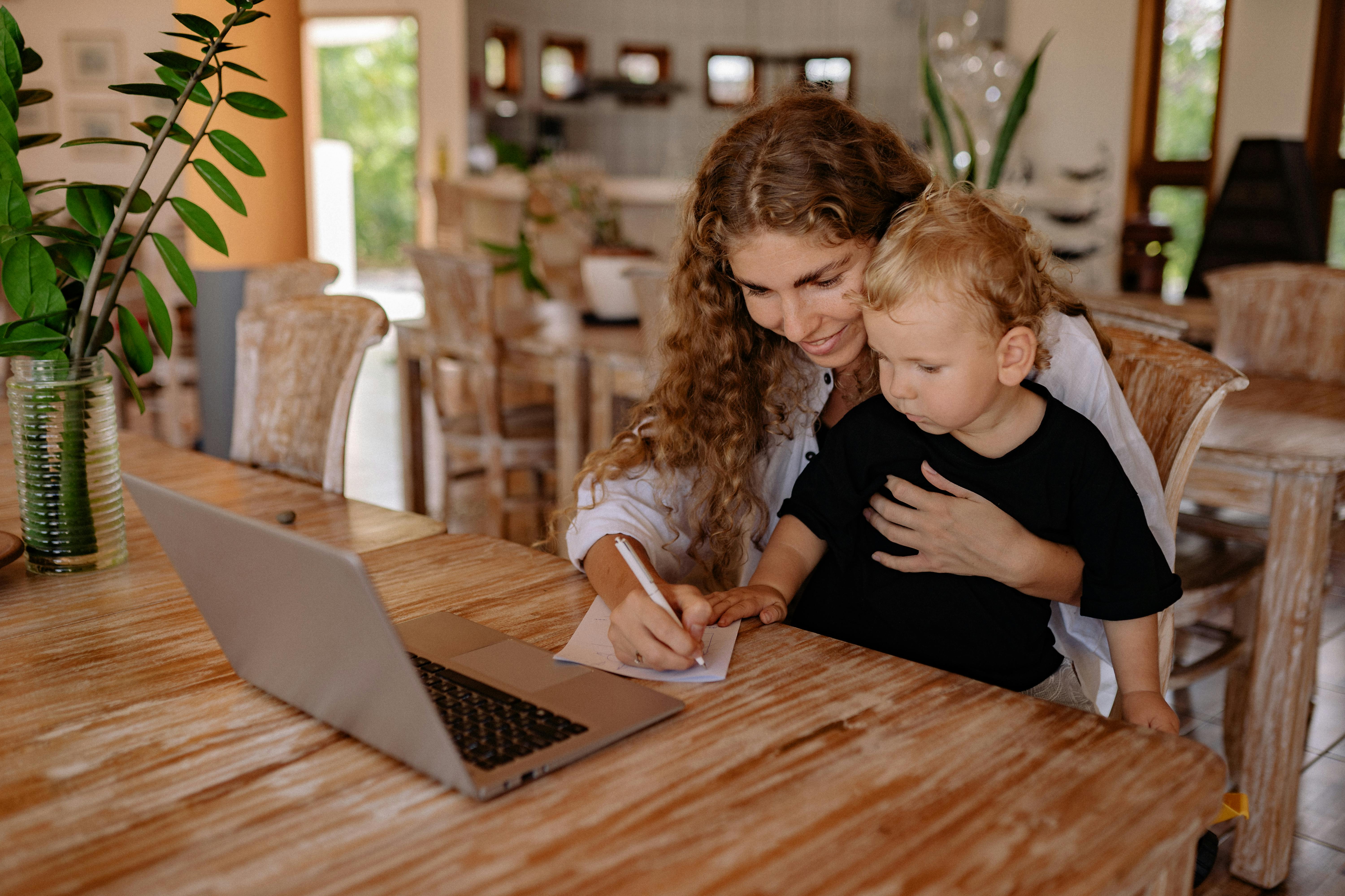 a woman writing on the paper with her son