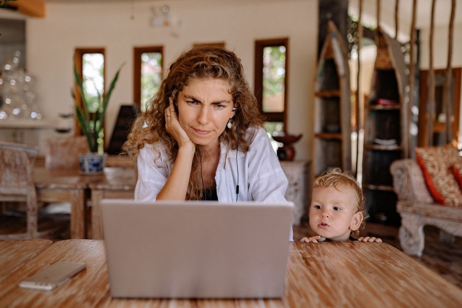 Madre y su hijo pequeño usando un laptop en una mesa de madera acogedora en interiores.