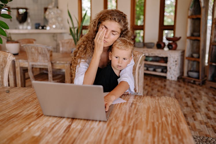 A Mother Using Laptop With Her Son