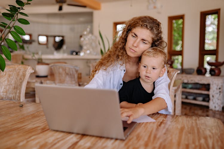 A Mother Using Laptop With Her Son