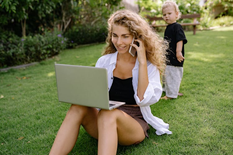 Busy Woman Sitting With Laptop On Grass