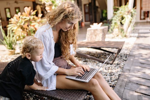 A Boy Beside a Woman Using a Computer Laptop