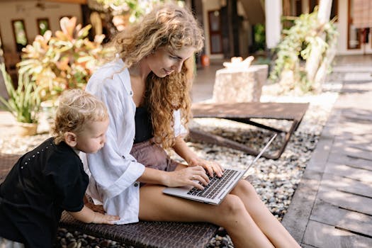 A woman and young boy enjoy a sunny day outdoors while using a laptop.