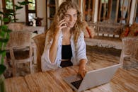 一位面带微笑的女士在一间装饰精美的家庭办公室里，一边用笔记本电脑工作，一边打电话