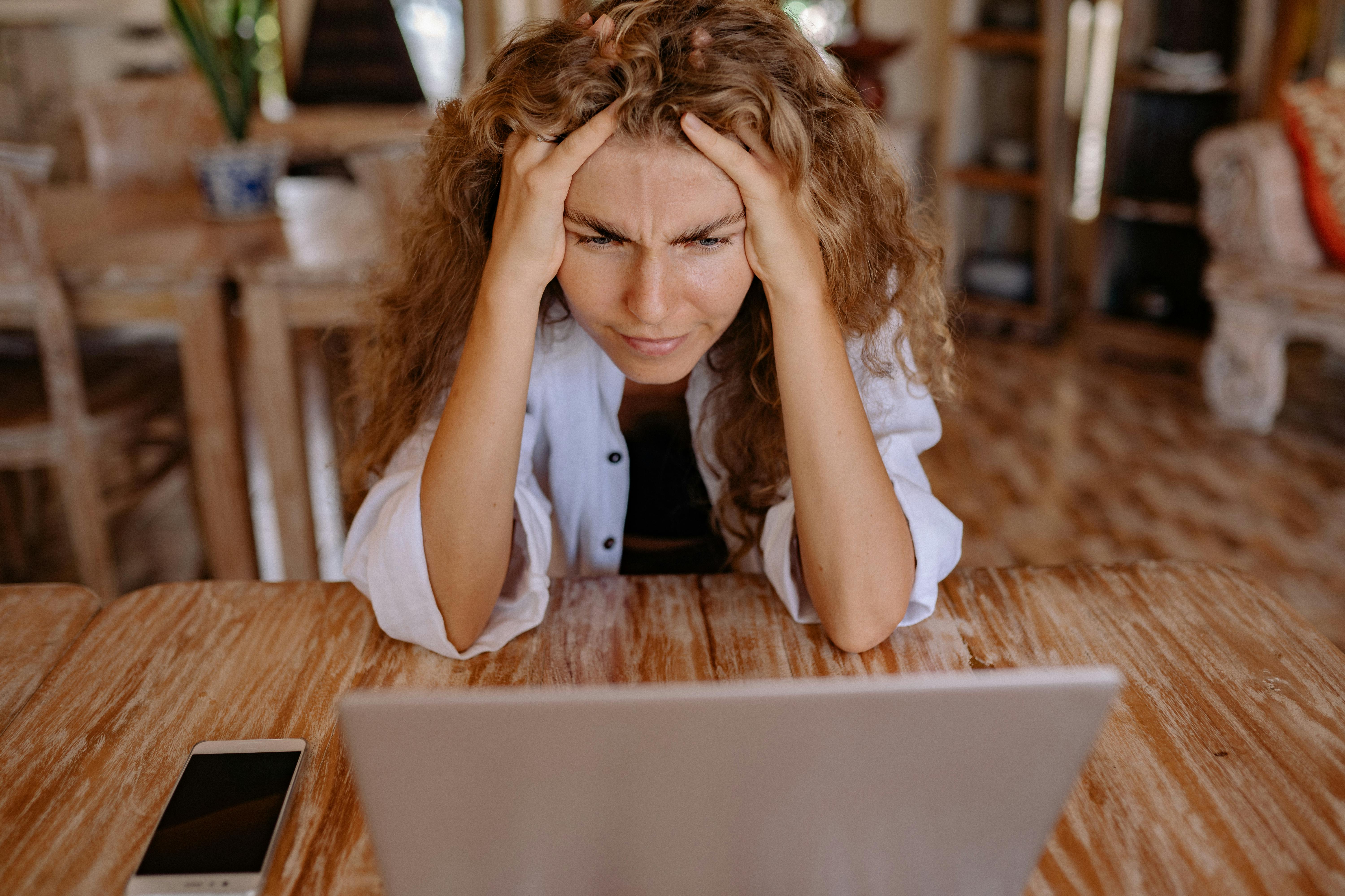 photo of woman leaning on wooden table while looking upset