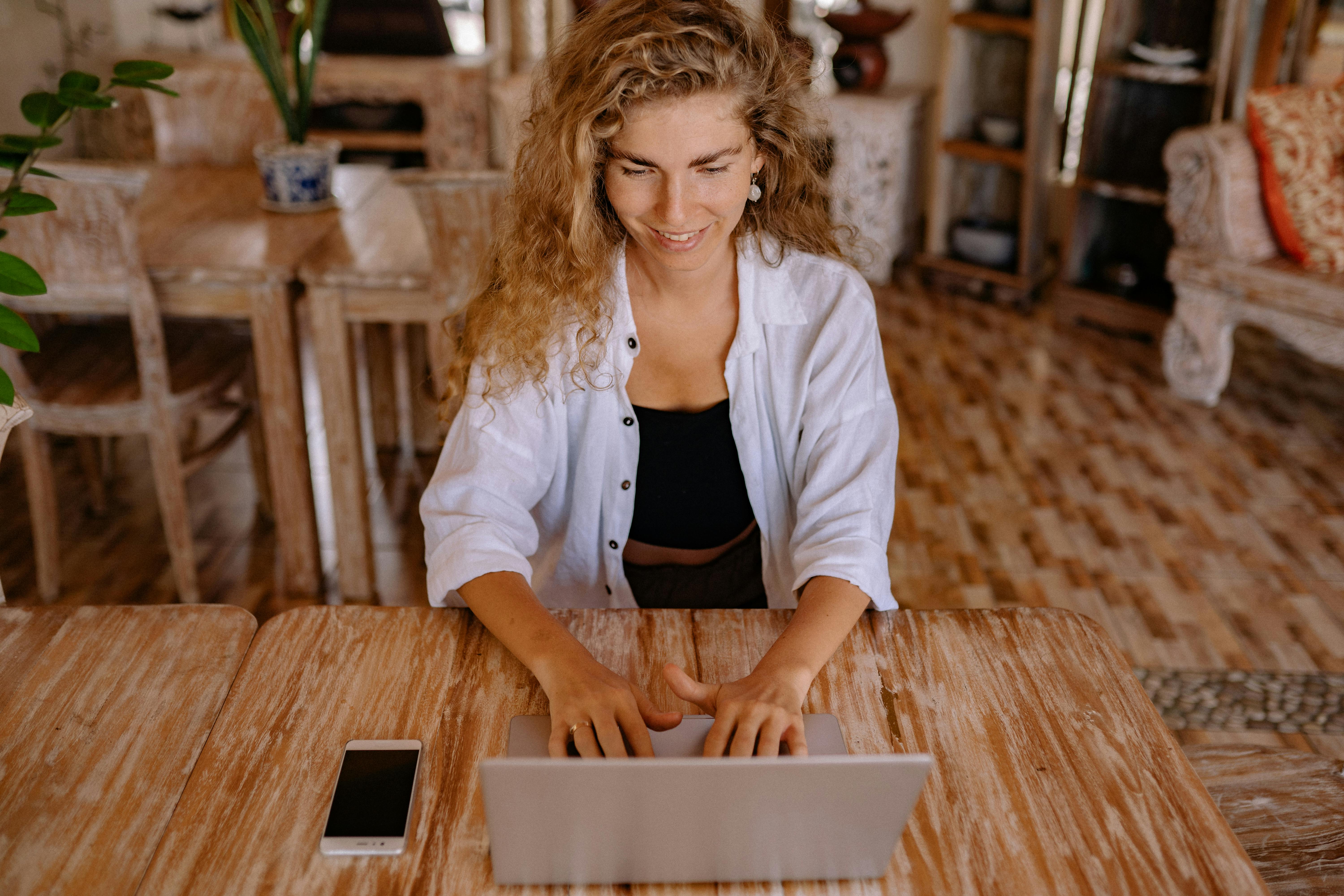 photo of woman using silver laptop while smiling