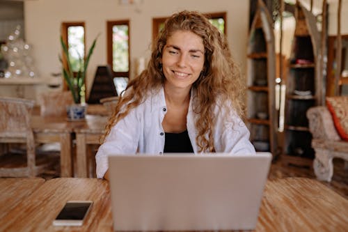 Photo of Woman Smiling While Using Laptop