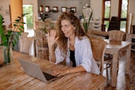 Woman in White Shirt Sitting on Chair in Front of Macbook