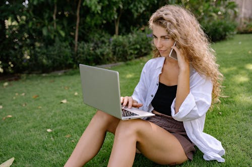 Woman Sitting on Green Grass Field Using Silver Macbook