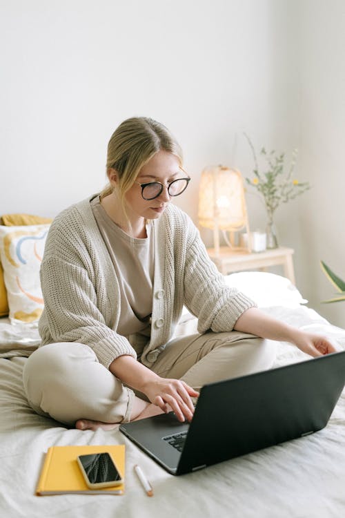 Photo of Woman Sitting on Bed While Using Black Laptop