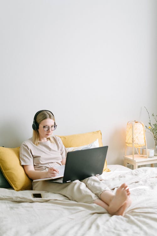 Free Photo of Woman Sitting on Bed While Using Black Laptop Stock Photo