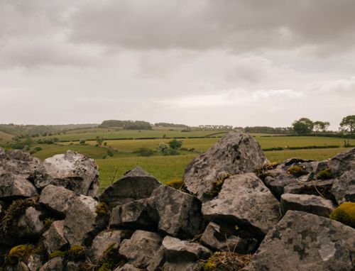 Free Rough stone boulders located near grassy terrain against cloudy sky in countryside in gloomy day Stock Photo