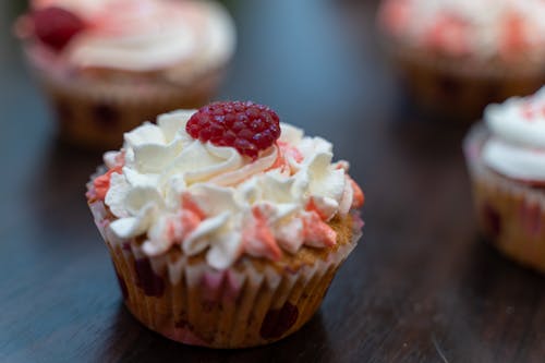 White and Brown Cupcake With White Icing on Brown Wooden Table