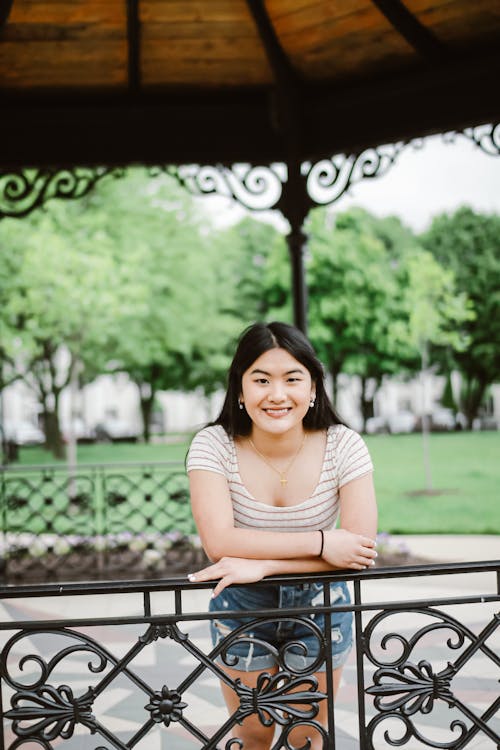 Positive Asian woman leaning on railing