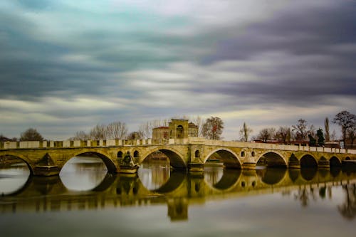 Old arched bridge over peaceful river on overcast day